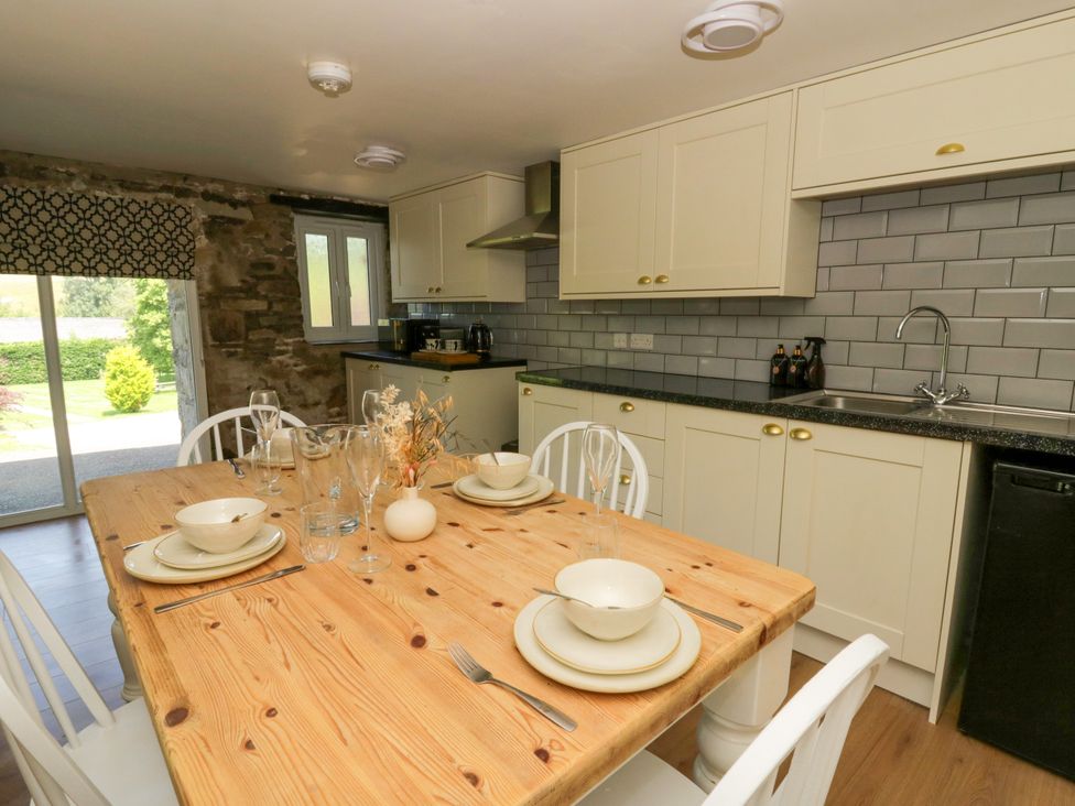 A kitchen with dining table and chairs at The Cart House in Pontsian