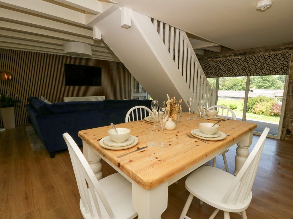 A dining room with a wooden table and chairs at The Cart House in Pontsian