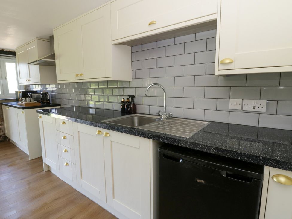 A kitchen with cabinets, sink and appliances at The Cart House in Pontsian