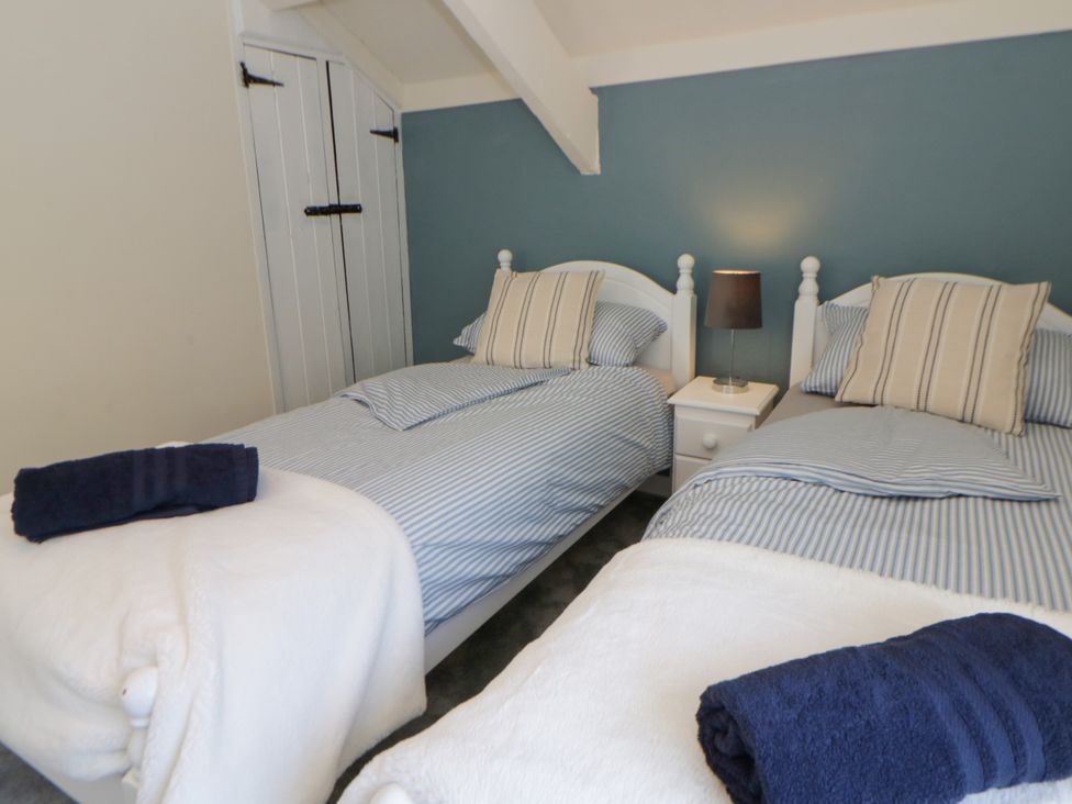 A bedroom with two single beds and a lamp on a nightstand at The Cart House in Pontsian