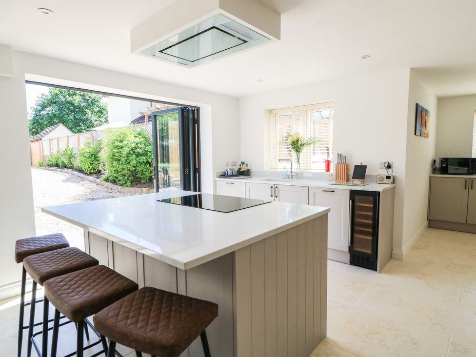 A kitchen with an island and bar stools at Cern-Wyn in Chippenham