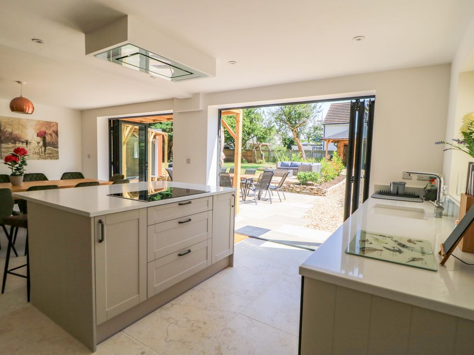 A kitchen with an island and sliding doors opening to a patio at Cern-Wyn in Chippenham