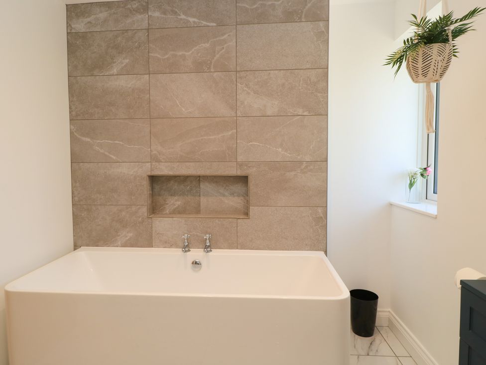 A bathroom with a bathtub and wall tiles at Cern-Wyn Chippenham