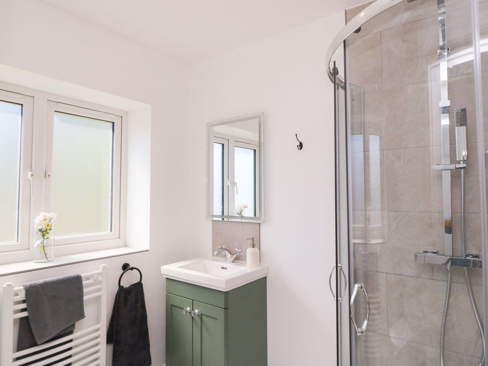 A bathroom featuring a shower, sink, and two windows at Cern-Wyn in Chippenham