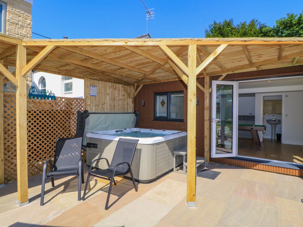 A hot tub with chairs under a wooden pergola at Cern-Wyn in Chippenham