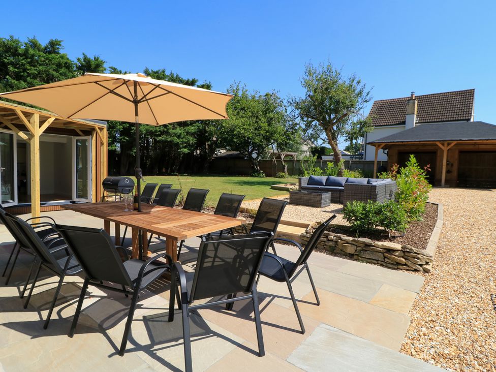 A garden with a dining table and chairs under an umbrella at Cern-Wyn in Chippenham