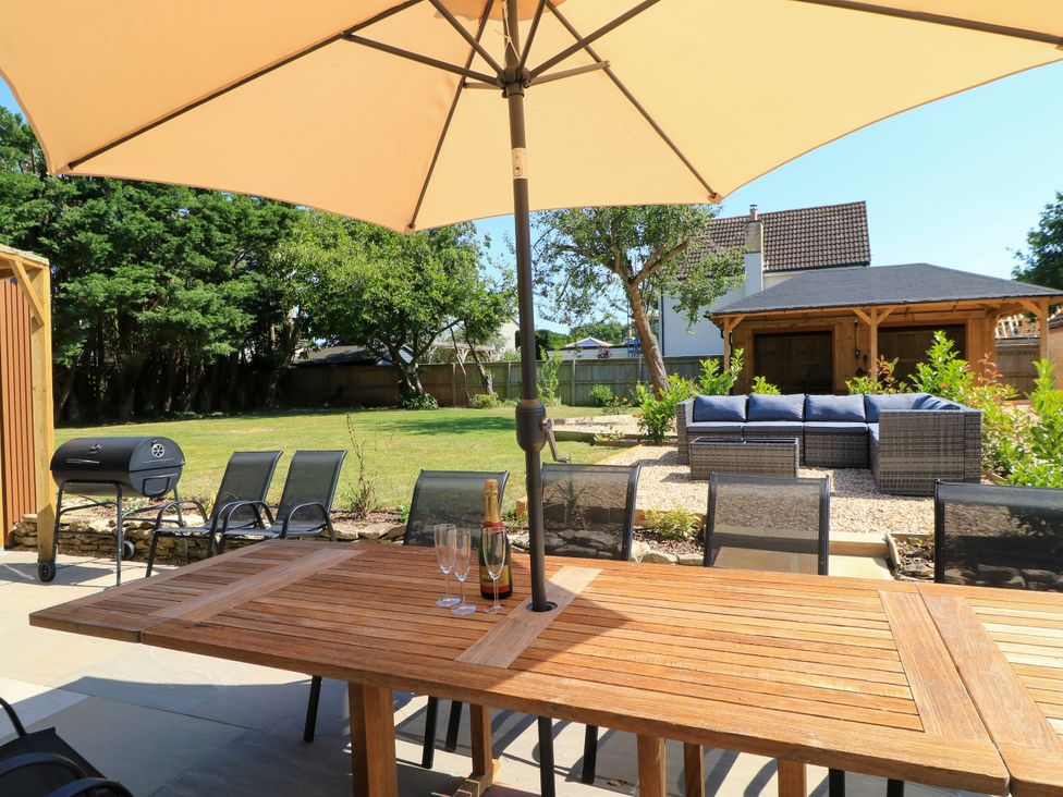 A garden with a table and chairs under an umbrella at Cern-Wyn in Chippenham