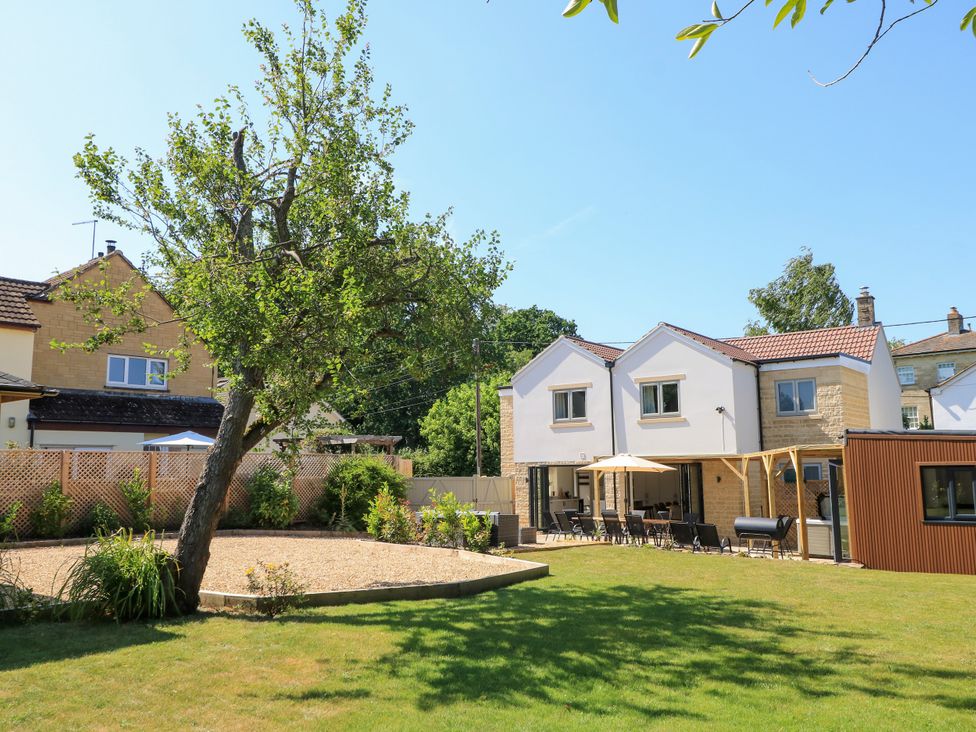A garden with a tree and seating area at Cern-Wyn in Chippenham