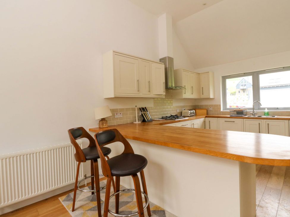 A kitchen with bar stools and kitchen cabinets at Craigard in Aberfeldy