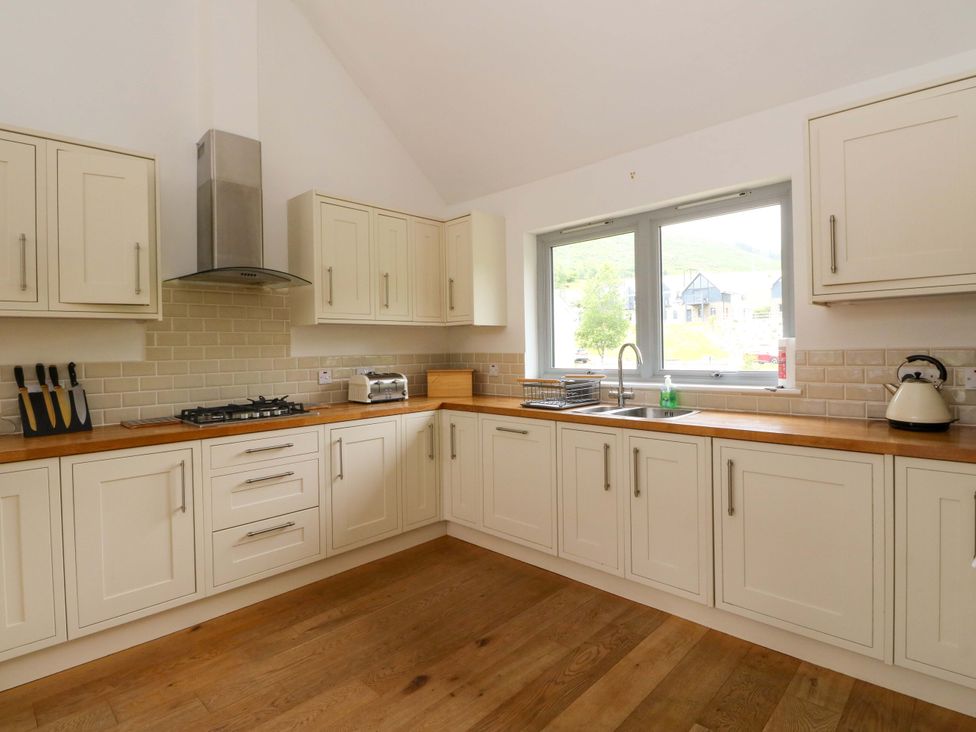 A kitchen with cabinets, sink, and stove at Craigard in Aberfeldy
