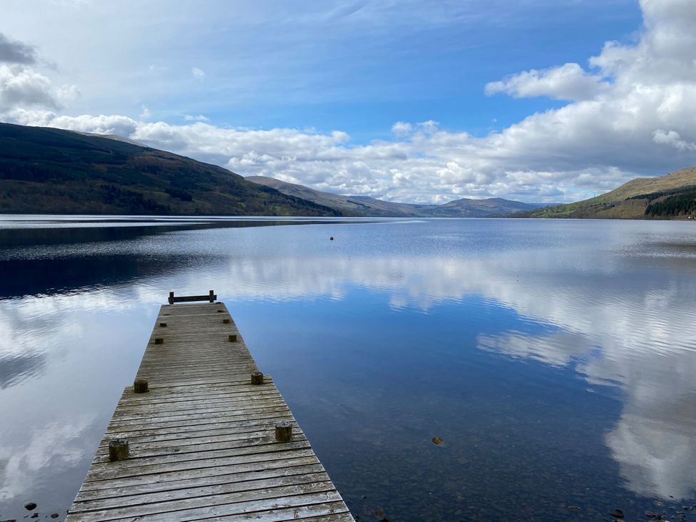 A pier extending over a lake with mountains in the background at Craigard in Aberfeldy
