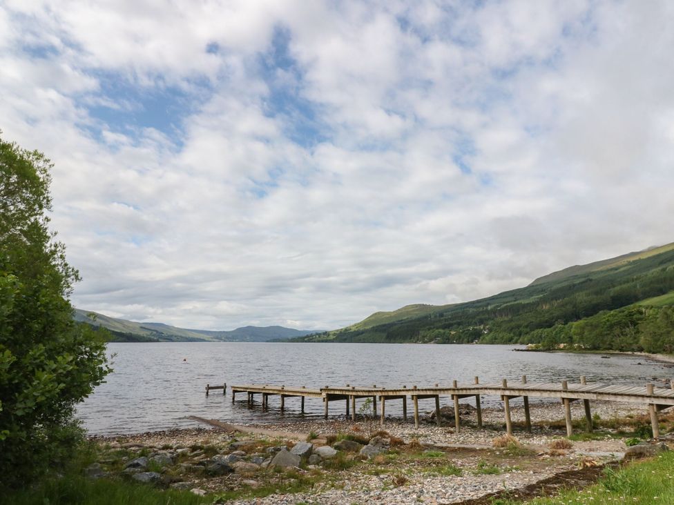 A lake with a wooden pier and trees at Craigard in Aberfeldy