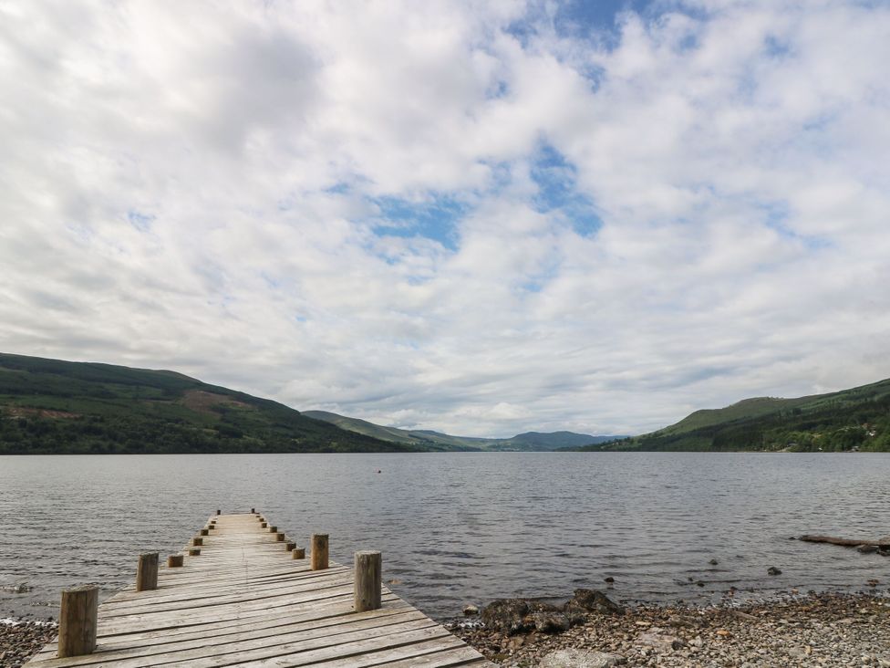 A pier extending into a lake with mountains in the background at Craigard in Aberfeldy
