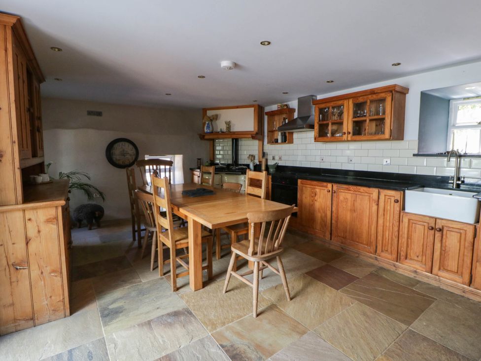 A kitchen with wooden cabinets and a dining table at Yr Hen Felin in Boncath