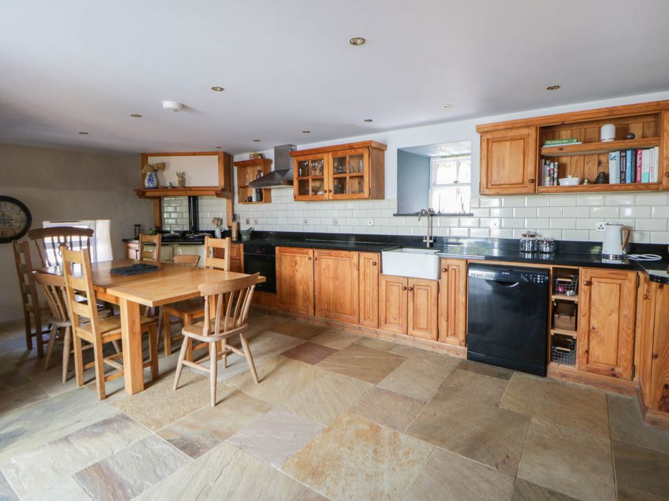 A kitchen with wooden cabinets and a dining table at Yr Hen Felin Boncath