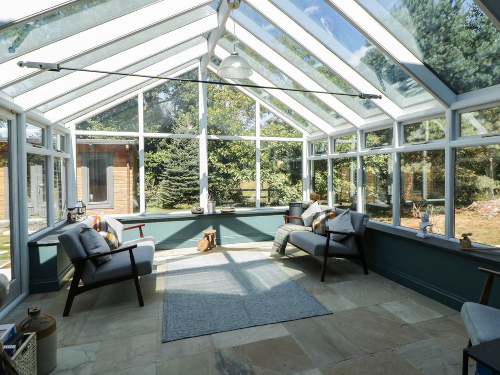 A conservatory with seating and windows at Yr Hen Felin in Boncath