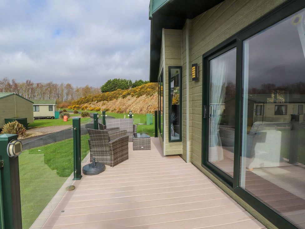A deck area with chairs and a table at 56 The Stables Pwllheli
