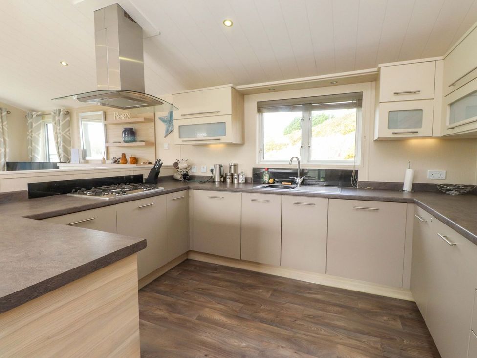 A kitchen with cabinets, sink, and gas stove at 56 The Stables in Pwllheli