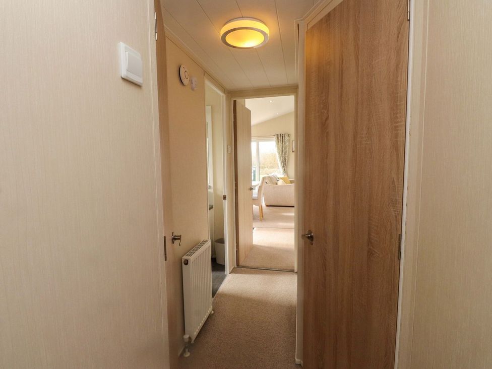 A hallway with doors and a radiator at 56 The Stables in Pwllheli