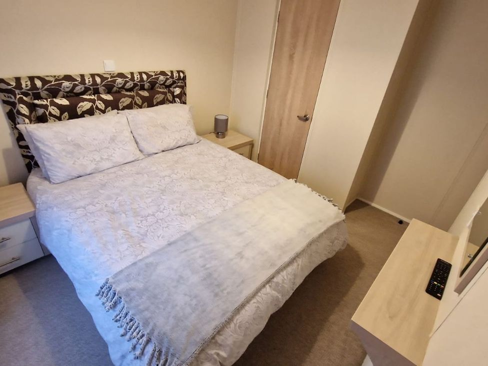 A bedroom with a bed and bedside table at 56 The Stables in Pwllheli
