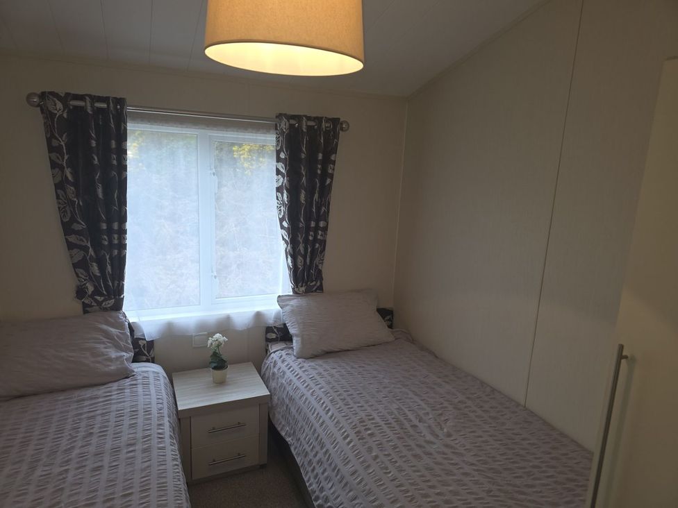 A bedroom with two single beds and a window at 56 The Stables in Pwllheli