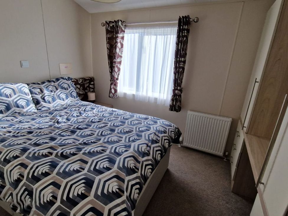 A bedroom with a bed and curtains at 56 The Stables in Pwllheli
