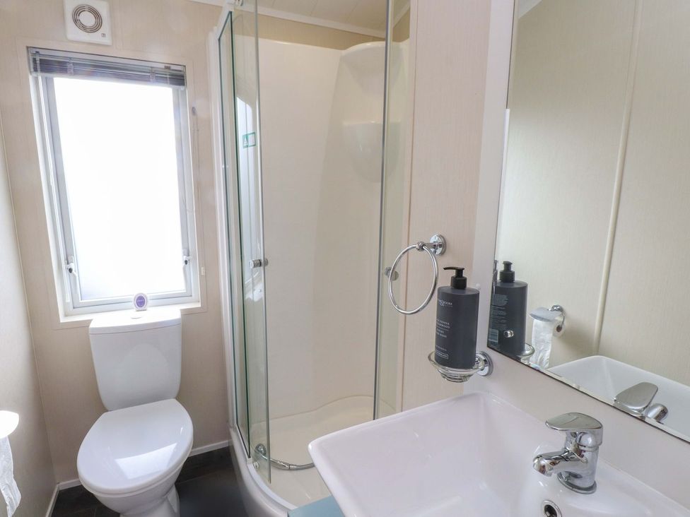 A bathroom with a shower, toilet, and sink at 56 The Stables Pwllheli