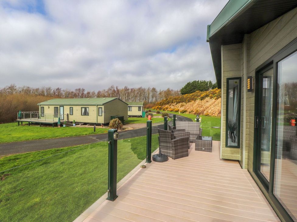 An outdoor view of caravans on a grassy area at 56 The Stables in Pwllheli