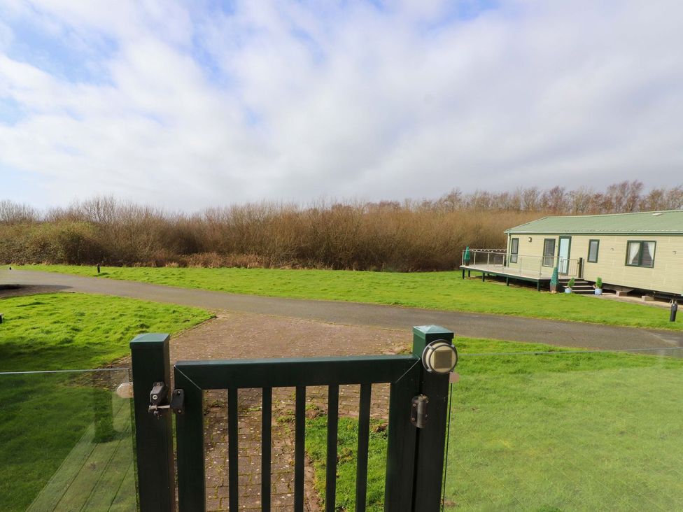 An outdoor area with a gate leading to a caravan at 56 The Stables in Pwllheli