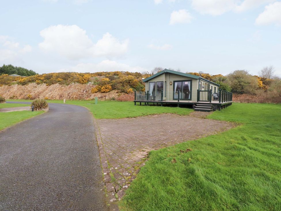 A house with decking and surrounding grass at 56 The Stables Pwllheli