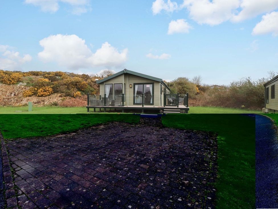 A house with a deck and grass area at 56 The Stables in Pwllheli
