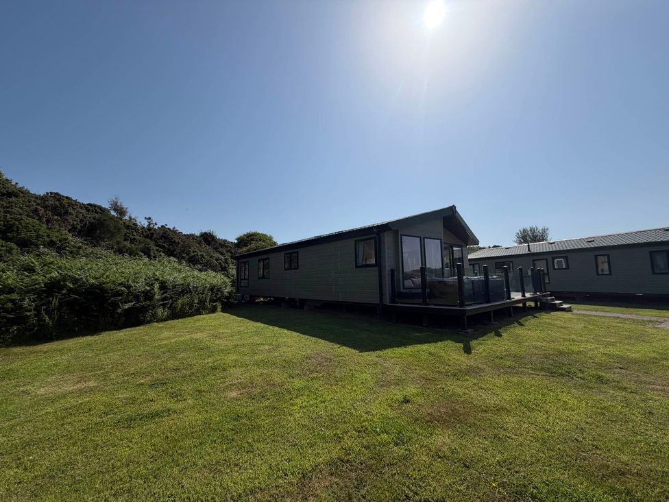 A cabin with a deck on grass at The Stables in Pwllheli