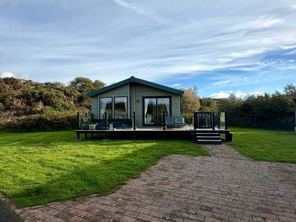 A house with a deck and glass doors in an outdoor area at The Stables in Pwllheli