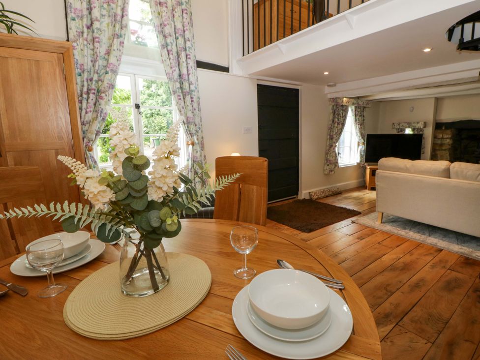 A dining room with a table set for two and a sofa with a television screen at Eightlands Hereford