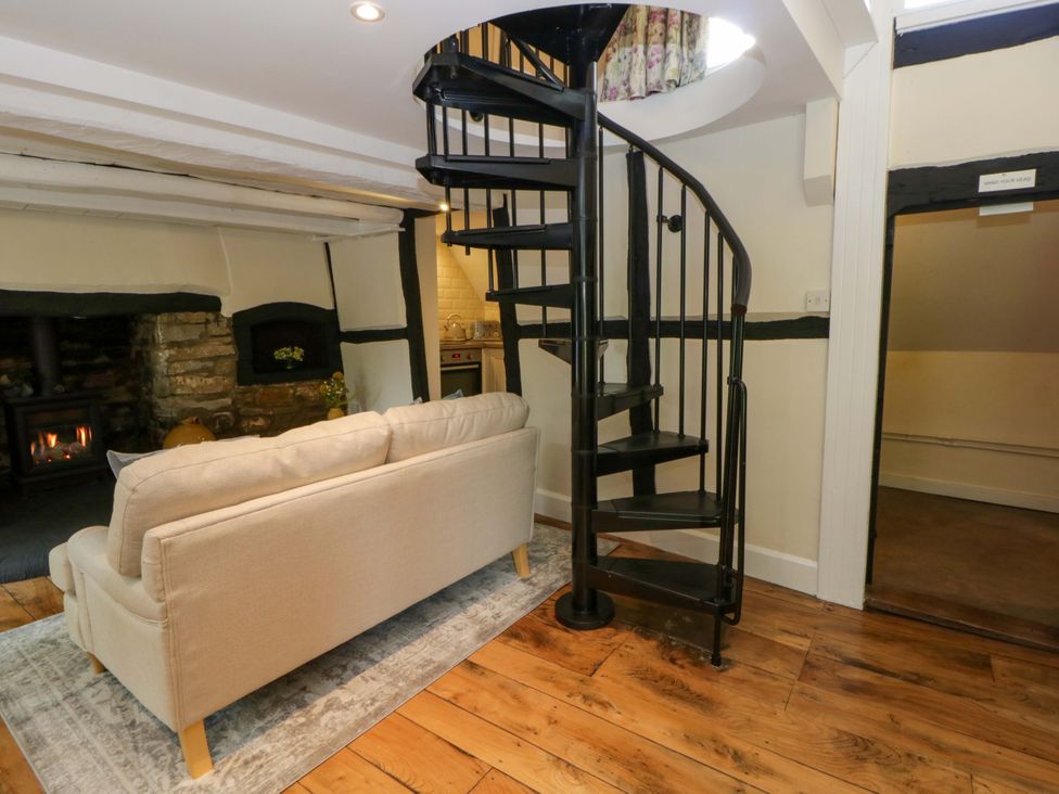 A living room with a sofa and spiral staircase at Eightlands in Hereford