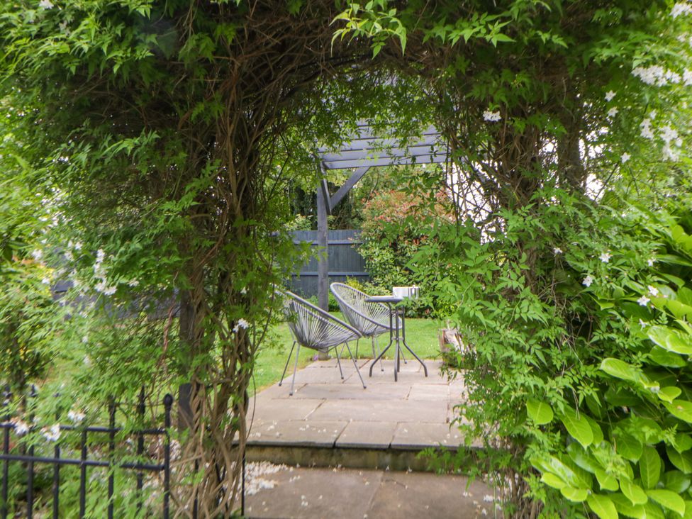 A garden with an archway leading to outdoor seating at Eightlands in Hereford
