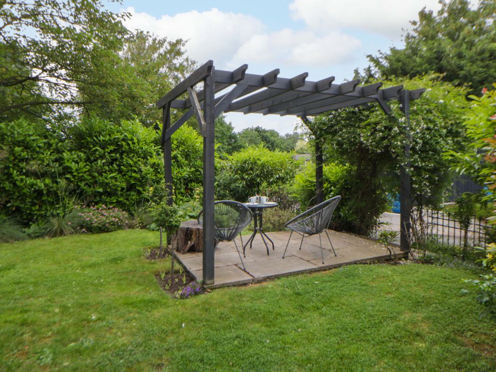 A garden with a pergola and seating area at Eightlands in Hereford