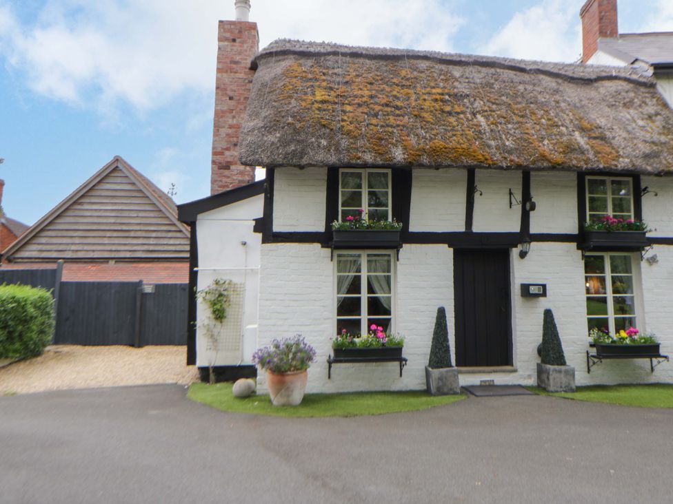 A cottage with a thatched roof and front garden at Eightlands in Hereford