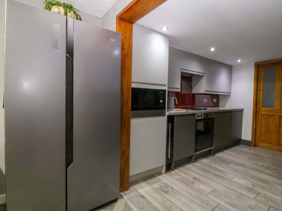 A kitchen with a refrigerator and modern appliances at Tyr Felin in Caernarfon