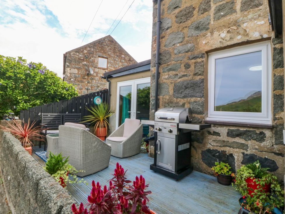 An outdoor patio with chairs and a grill at Tyr Felin near Trefor