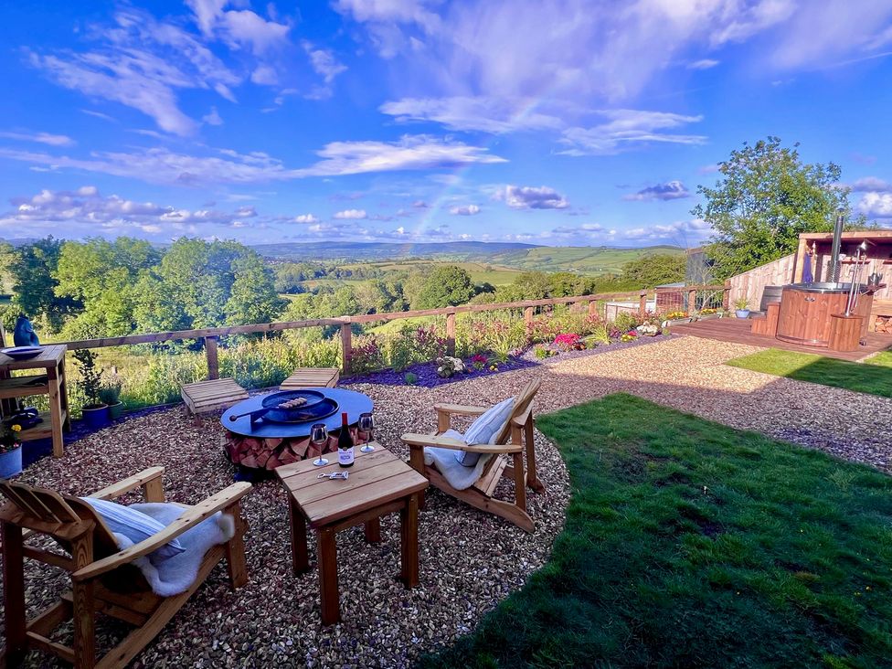 A garden with a fire pit and chairs at Olive Hut 