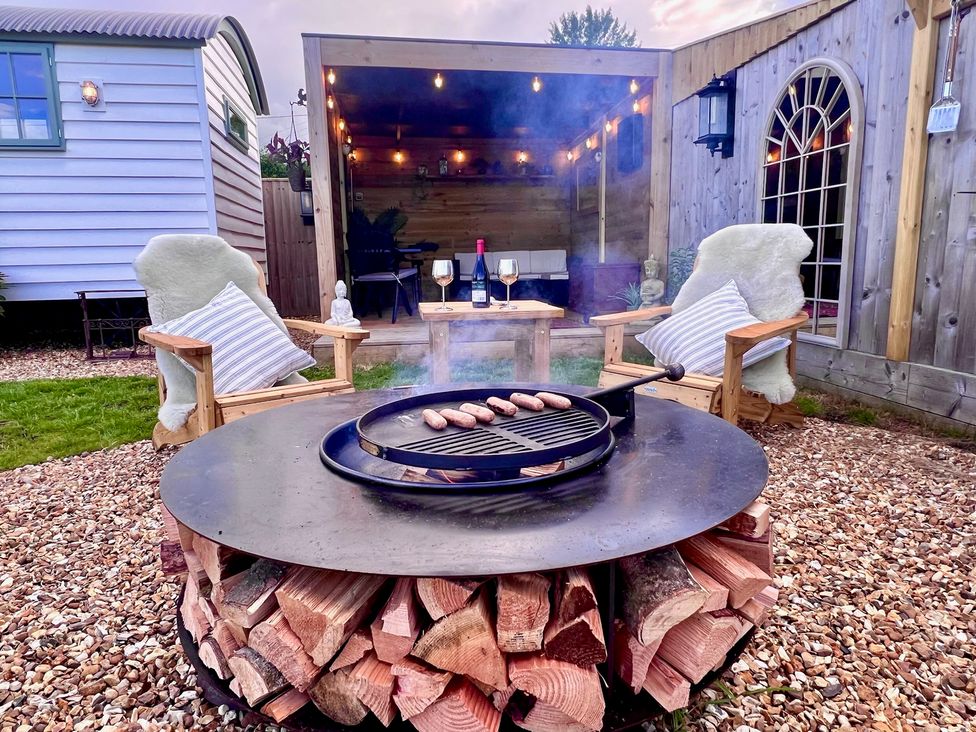 An outdoor grilling area with chairs and a table at Olive Hut