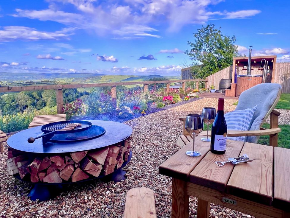 An outdoor area with a grill and wine on a table at Olive Hut