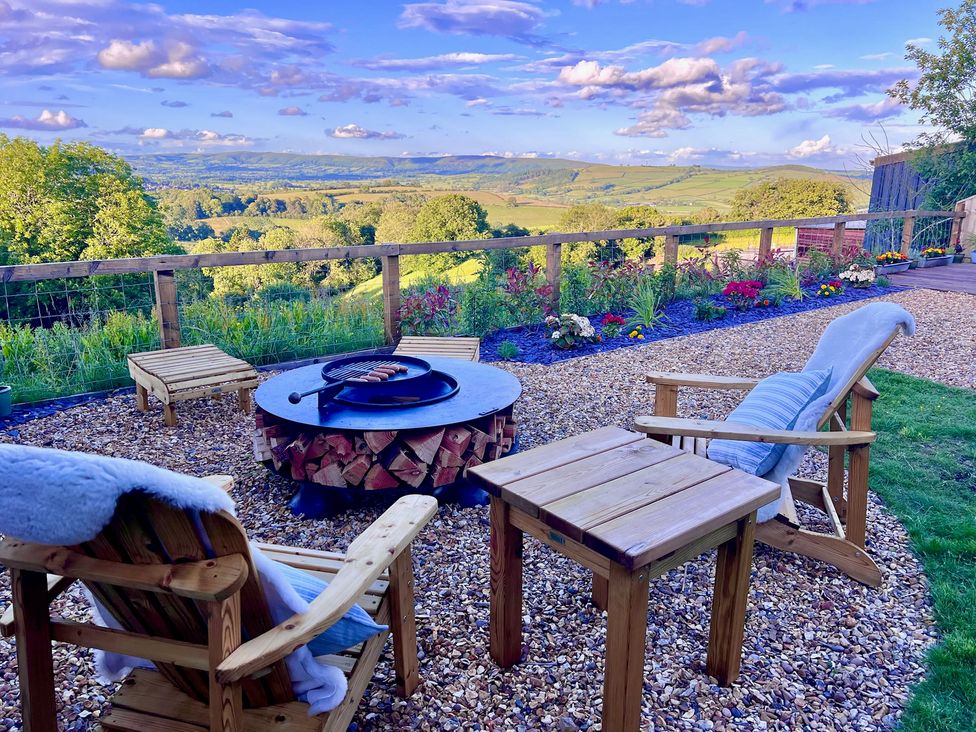 A garden with outdoor seating and a fire pit at Olive Hut 