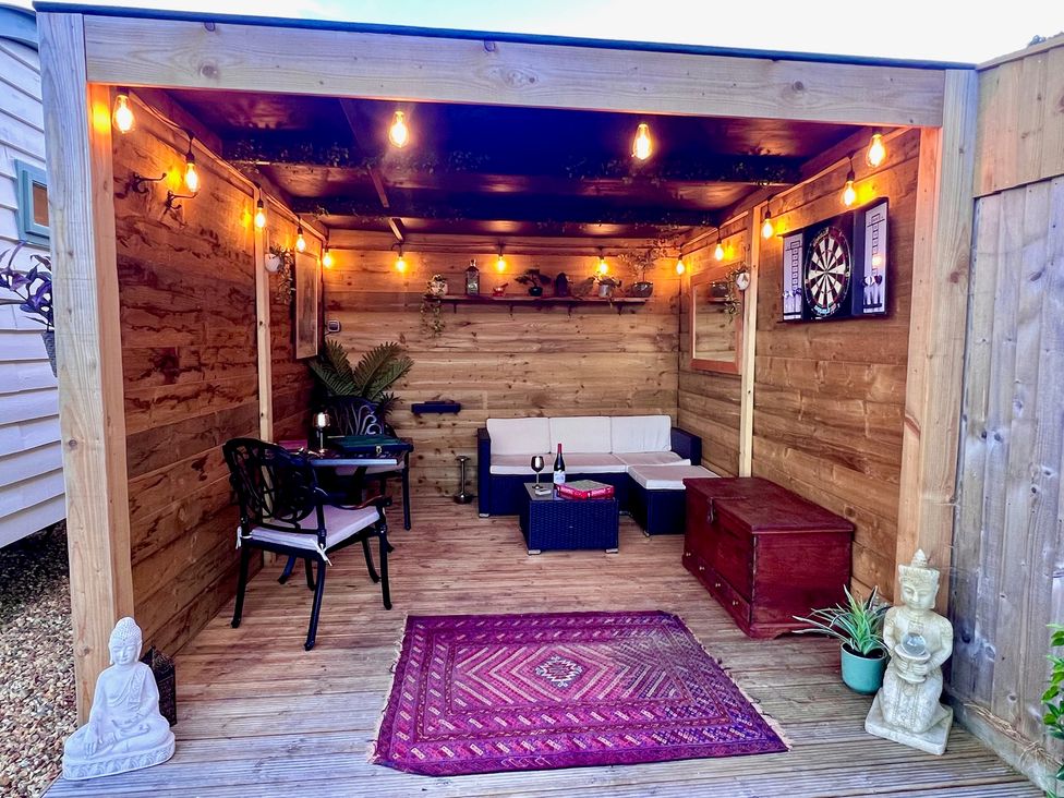 An outdoor sitting area with a sofa and dartboard at Olive Hut