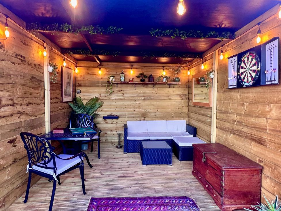 A snug with a sofa, table, and dartboard at Olive Hut