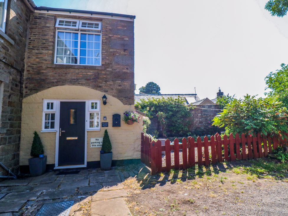 A door and windows with a stone wall and a fence at Arch Mews Cottage Middleton-In-Teesdale