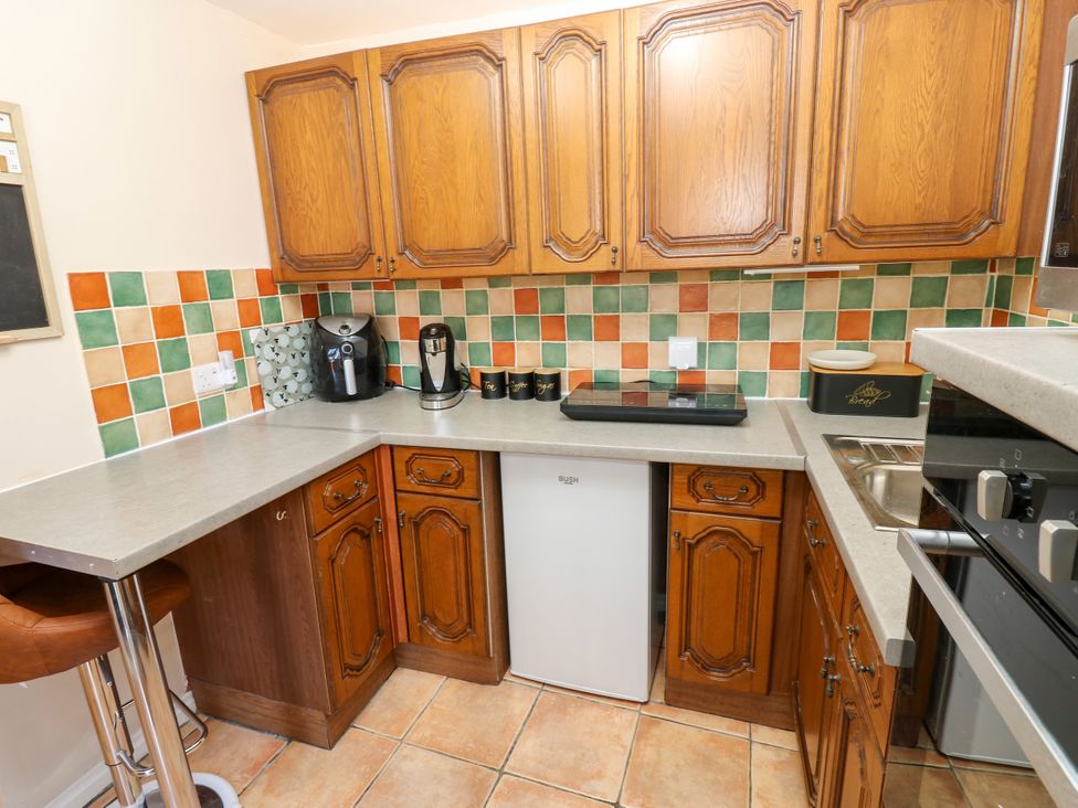 A kitchen with wooden cabinets and appliances at Arch Mews Cottage Middleton-In-Teesdale