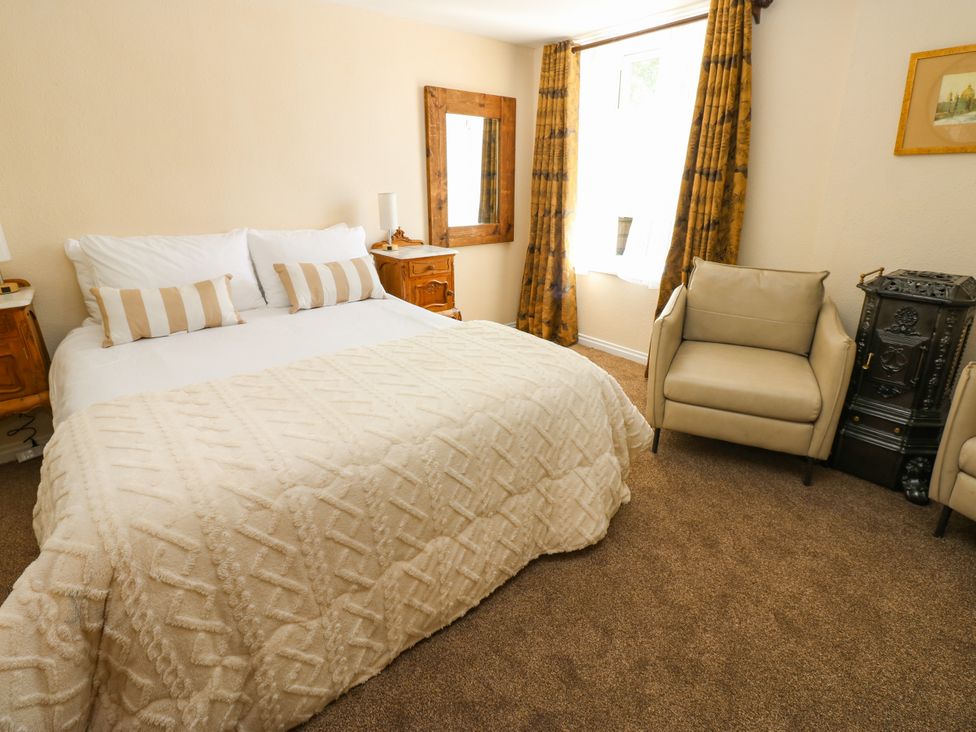 A bedroom with a bed and armchair at Arch Mews Cottage Middleton-In-Teesdale