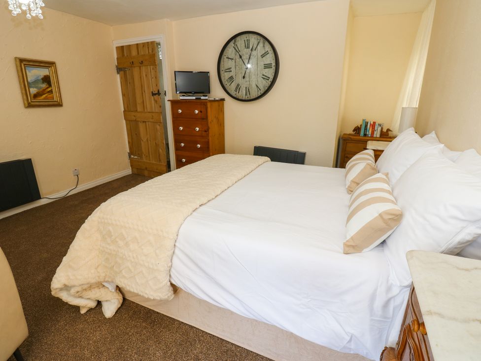 A bedroom with a bed and a clock on the wall at Arch Mews Cottage Middleton-In-Teesdale